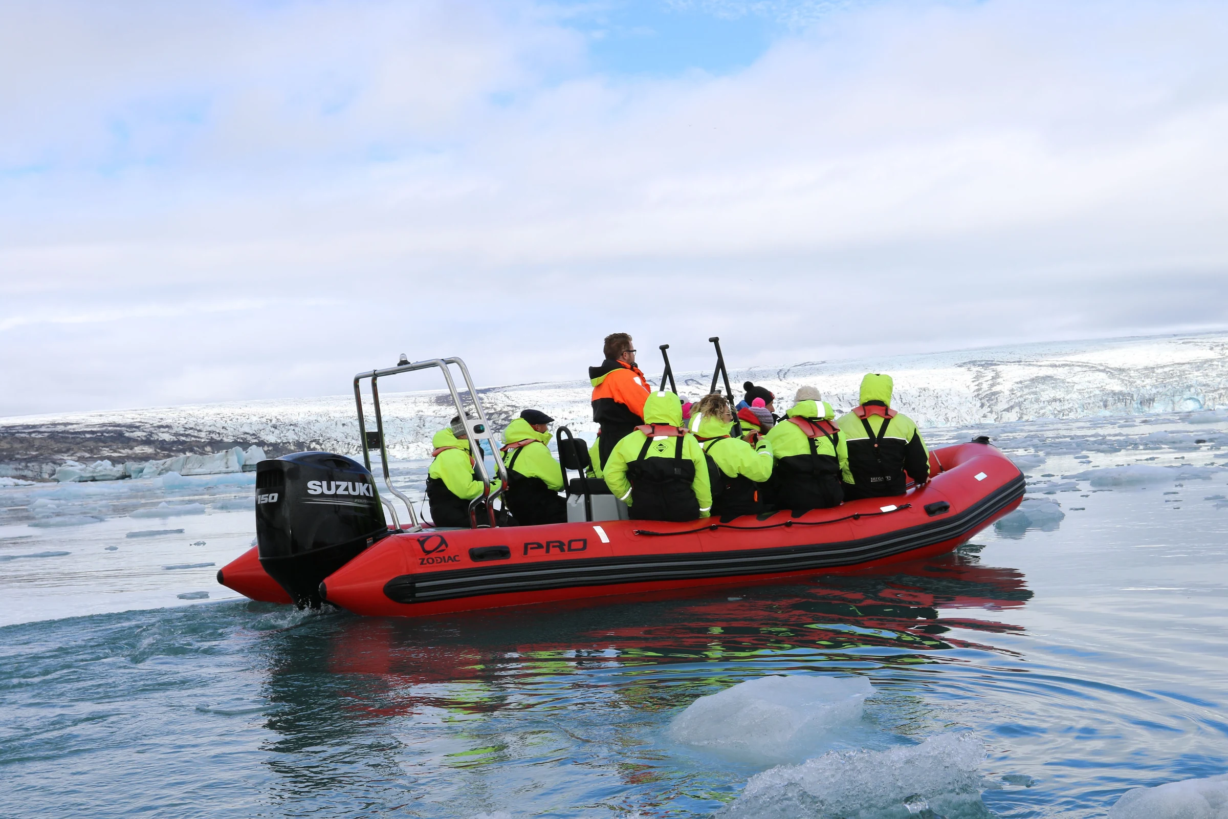 Expedition guests in a red Zodiac among Antarctic ice