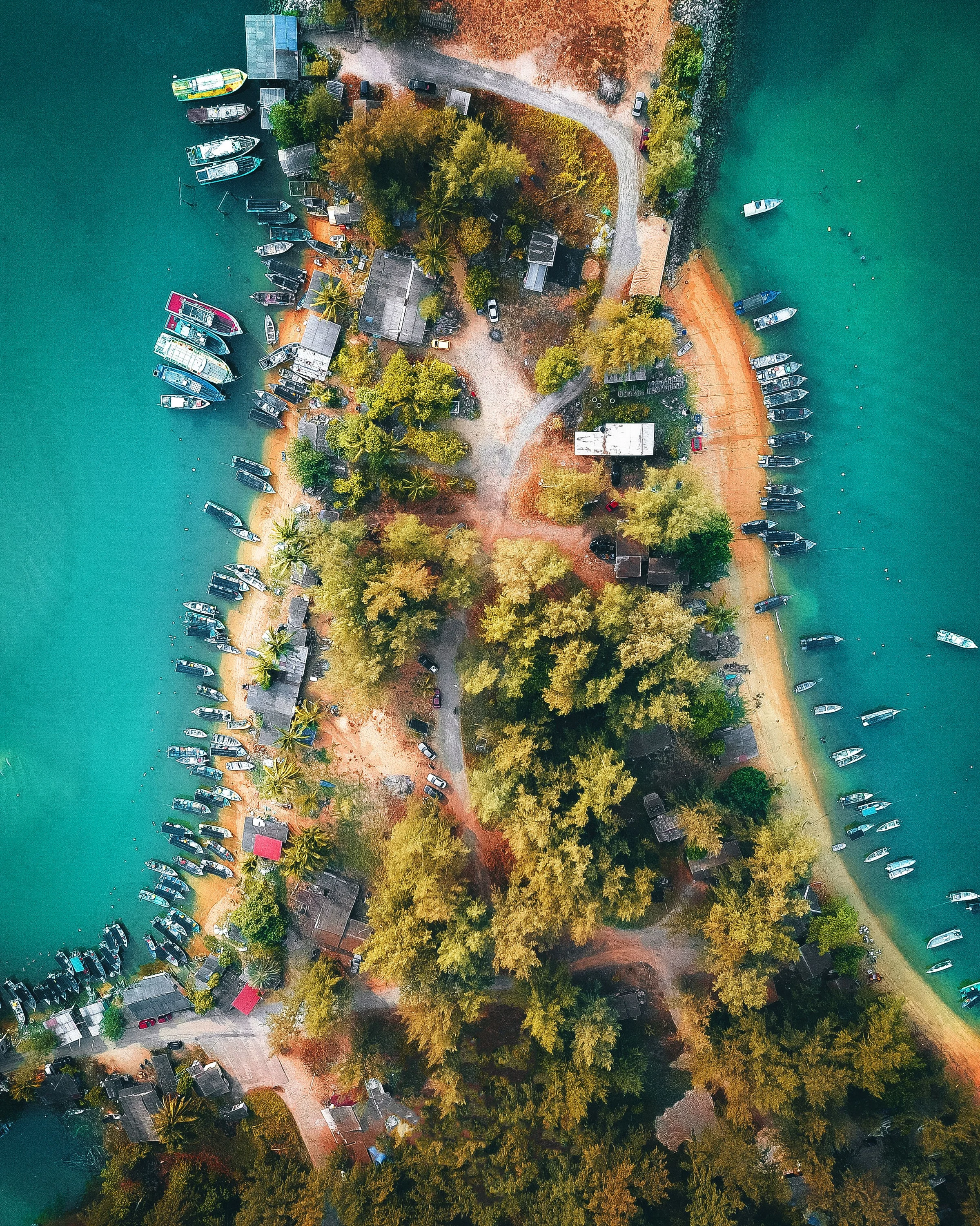 Aerial view of small boats along both sides of a narrow tropical shoreline