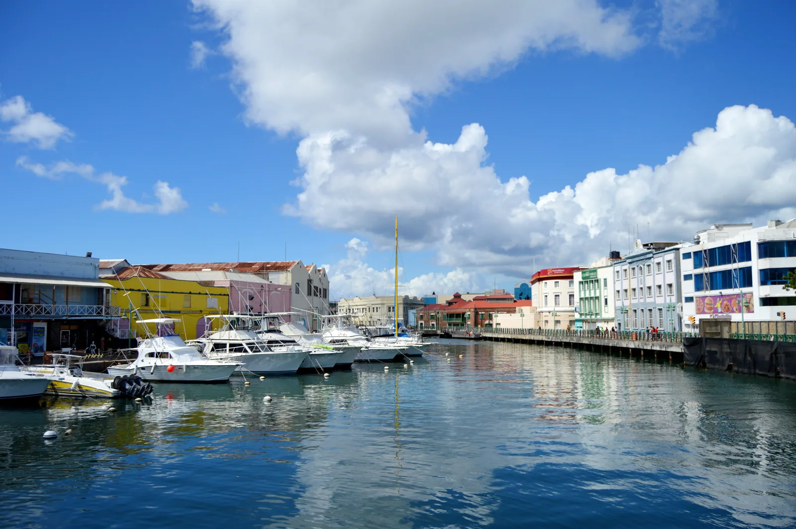 Boats moored beside colorful waterfront buildings in Bridgetown