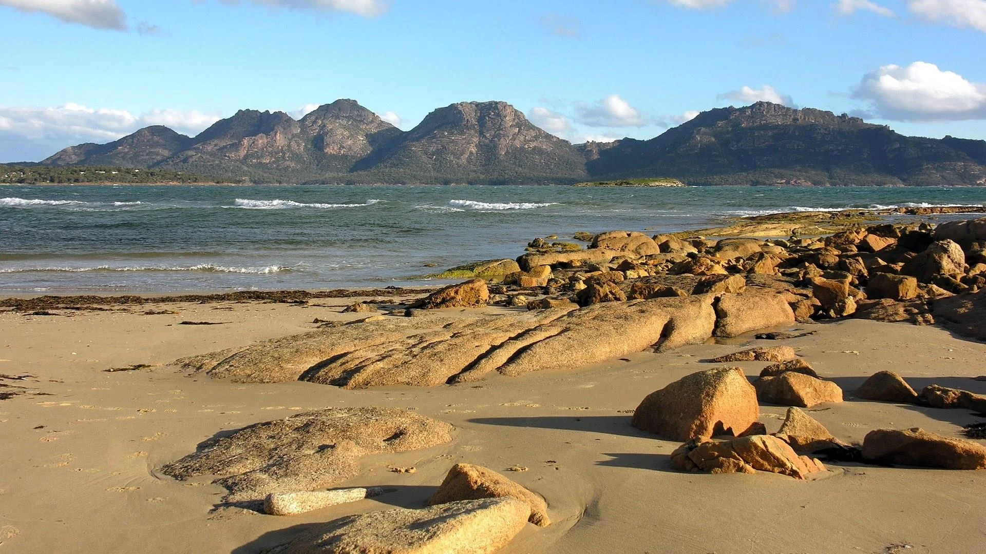 Rocky shoreline and mountains across the water at Freycinet, Tasmania