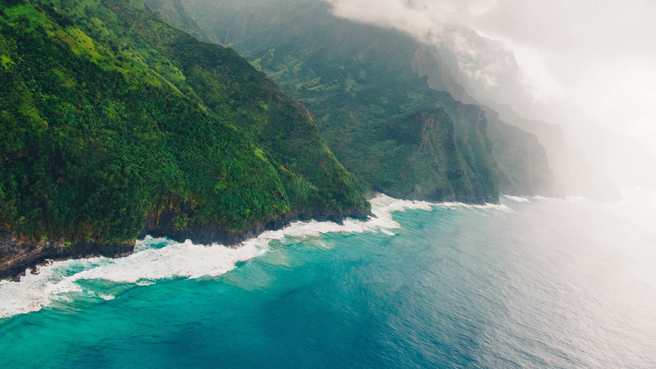 Green cliffs dropping into the ocean along Kauai’s Nā Pali Coast