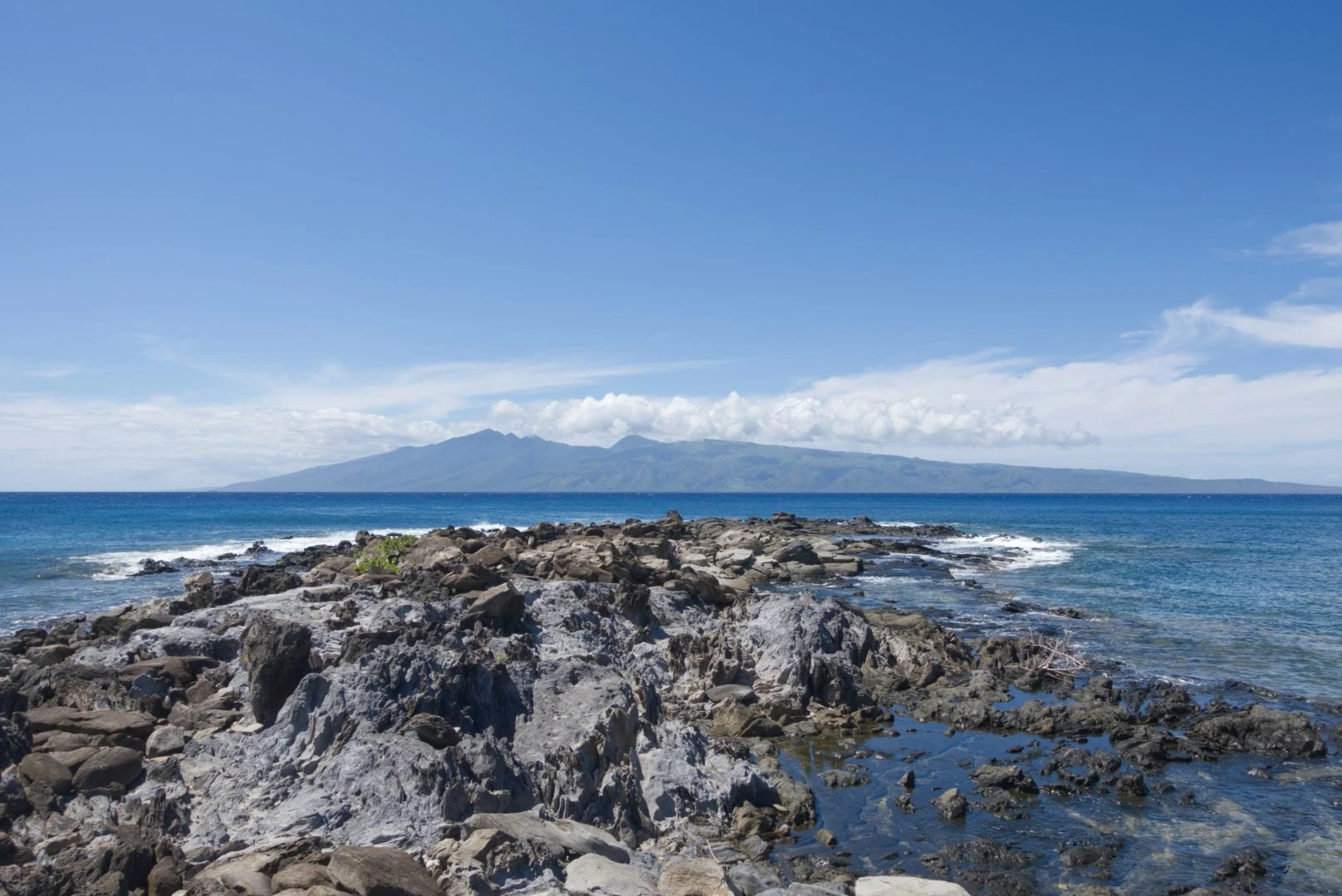 Rocky shoreline and island mountains across blue water