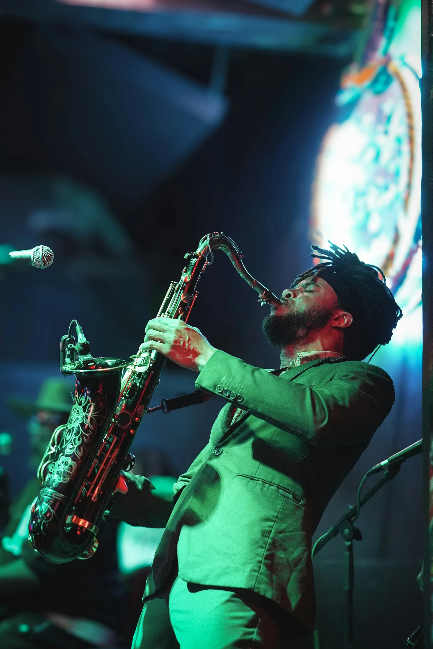 Saxophonist performing under green stage lighting