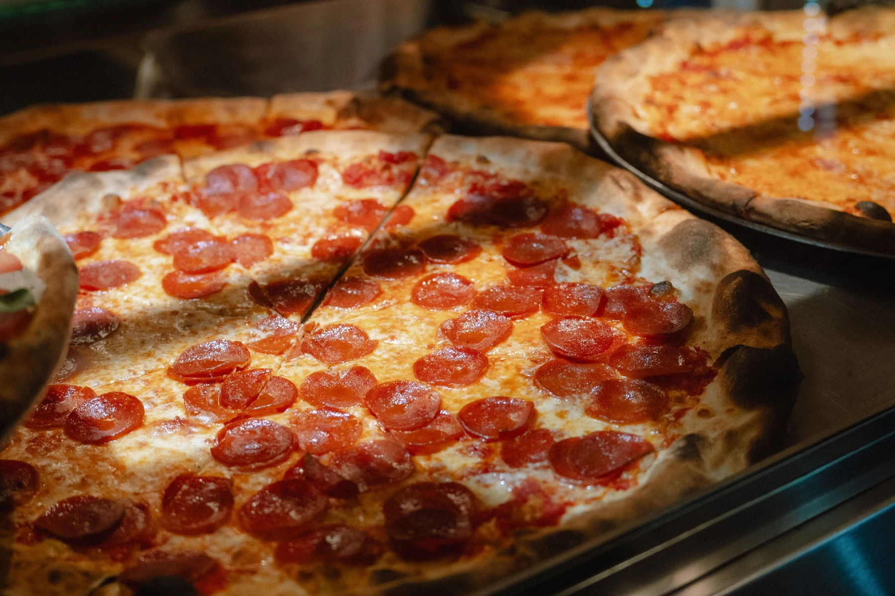 Freshly baked pizzas displayed at a New York City pizza shop