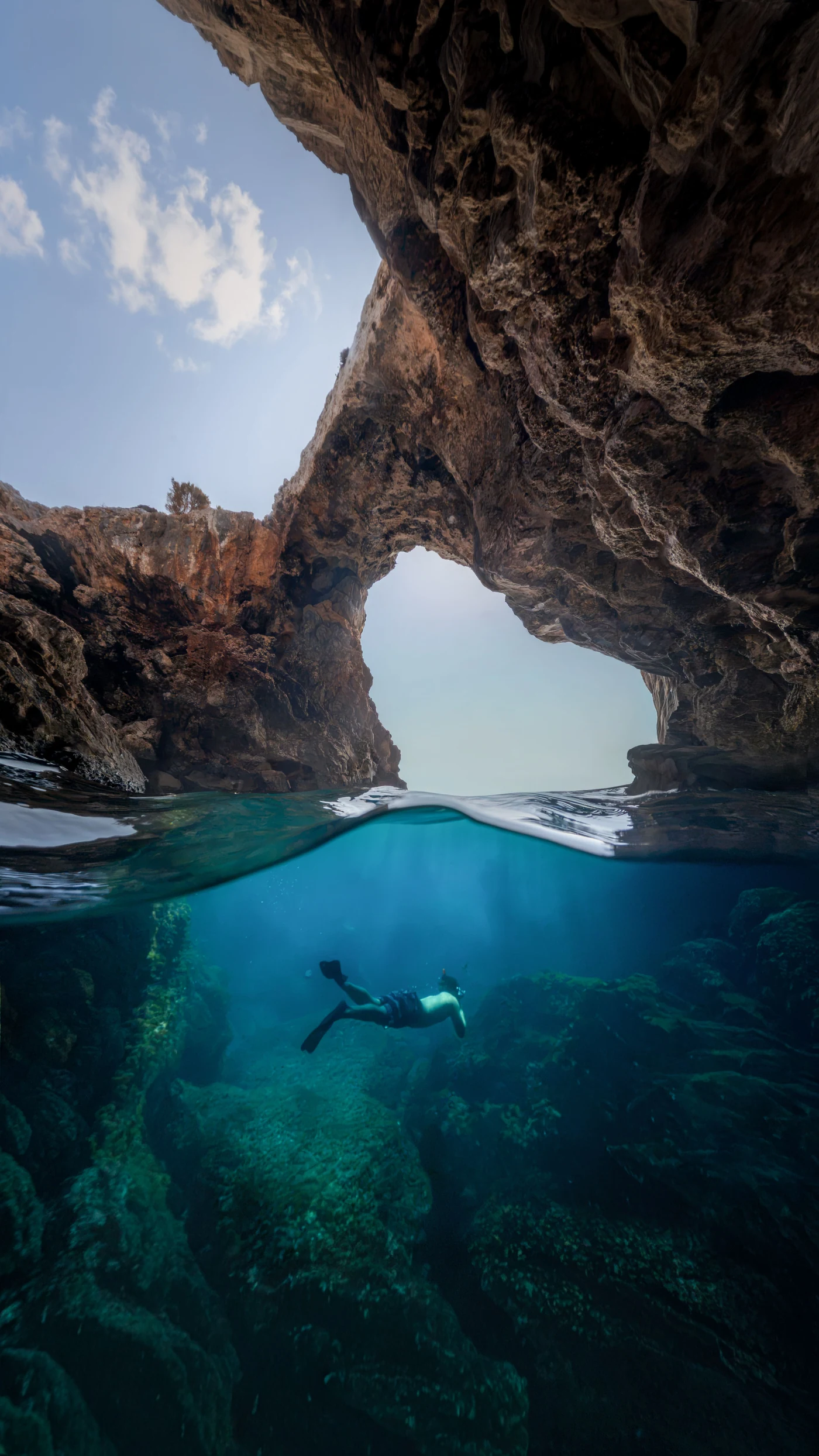 A swimmer beneath the water inside a coastal cave
