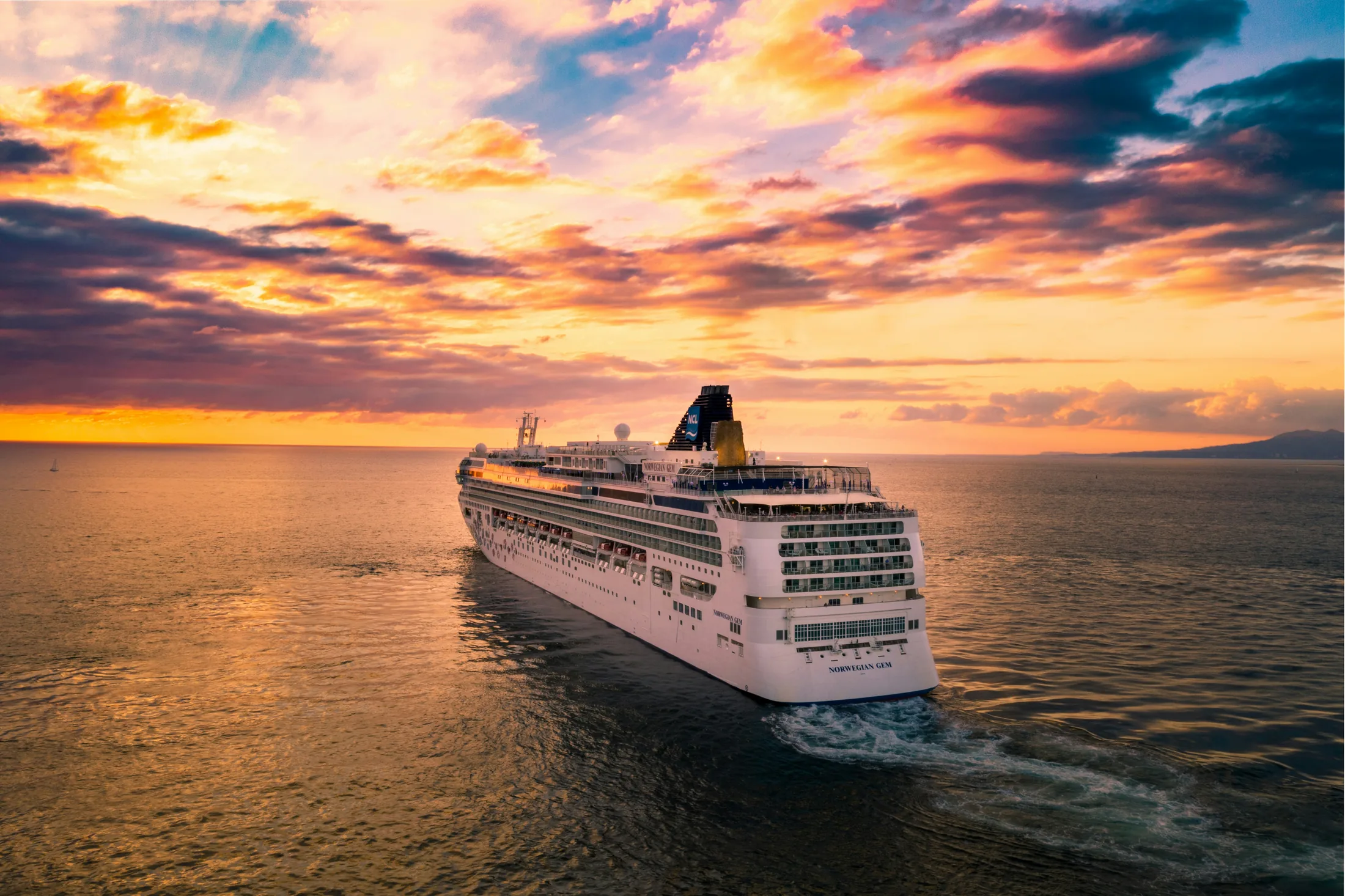Cruise ship at sea beneath a colorful sunset