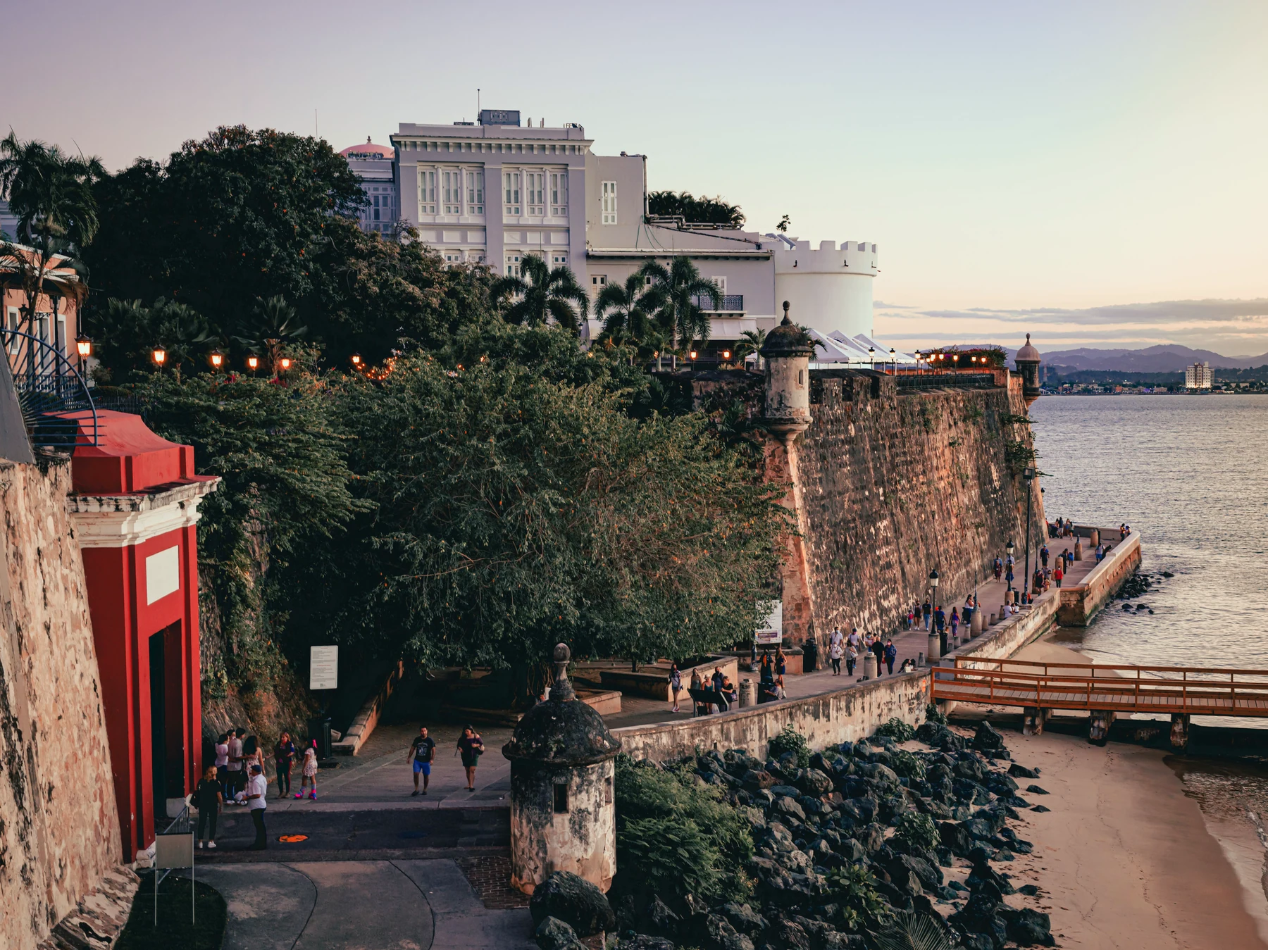 Historic stone walls, sentry towers and a waterfront promenade beneath evening light