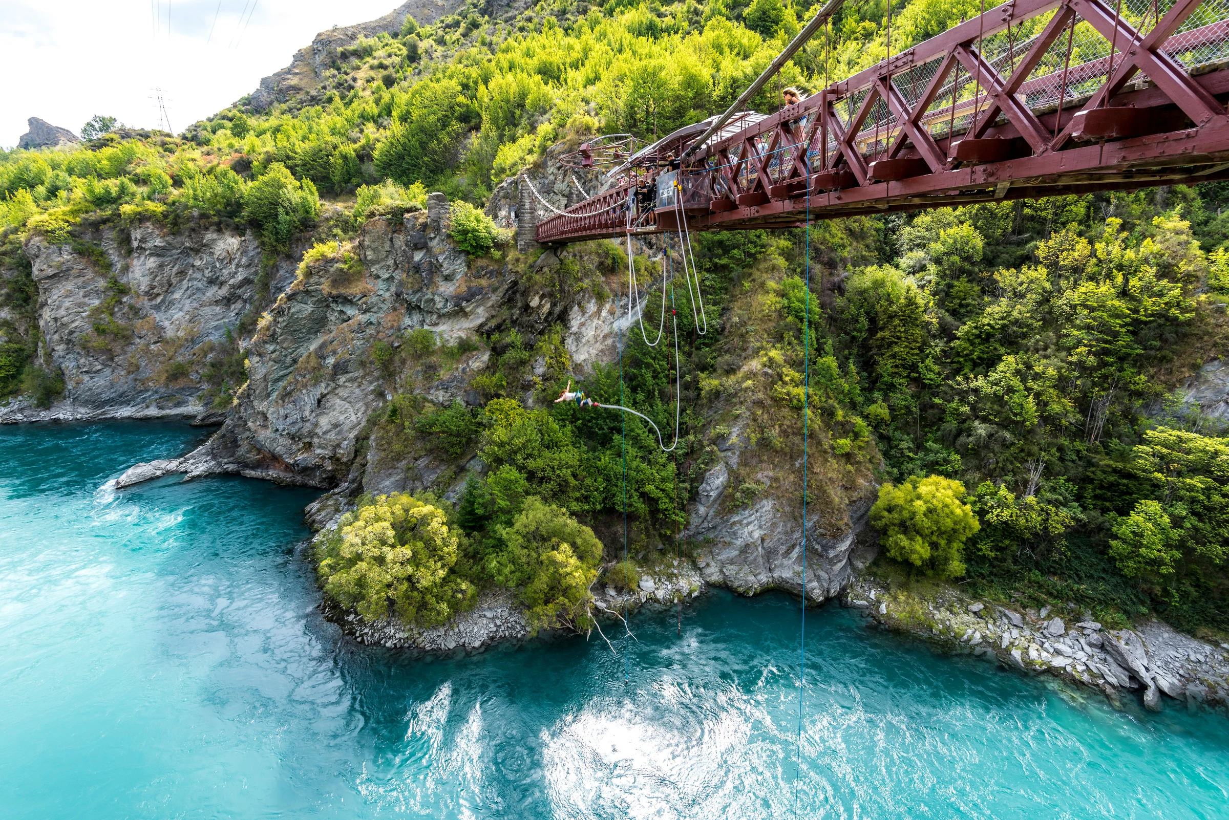 A bungy jumper below Kawarau Bridge above a turquoise river