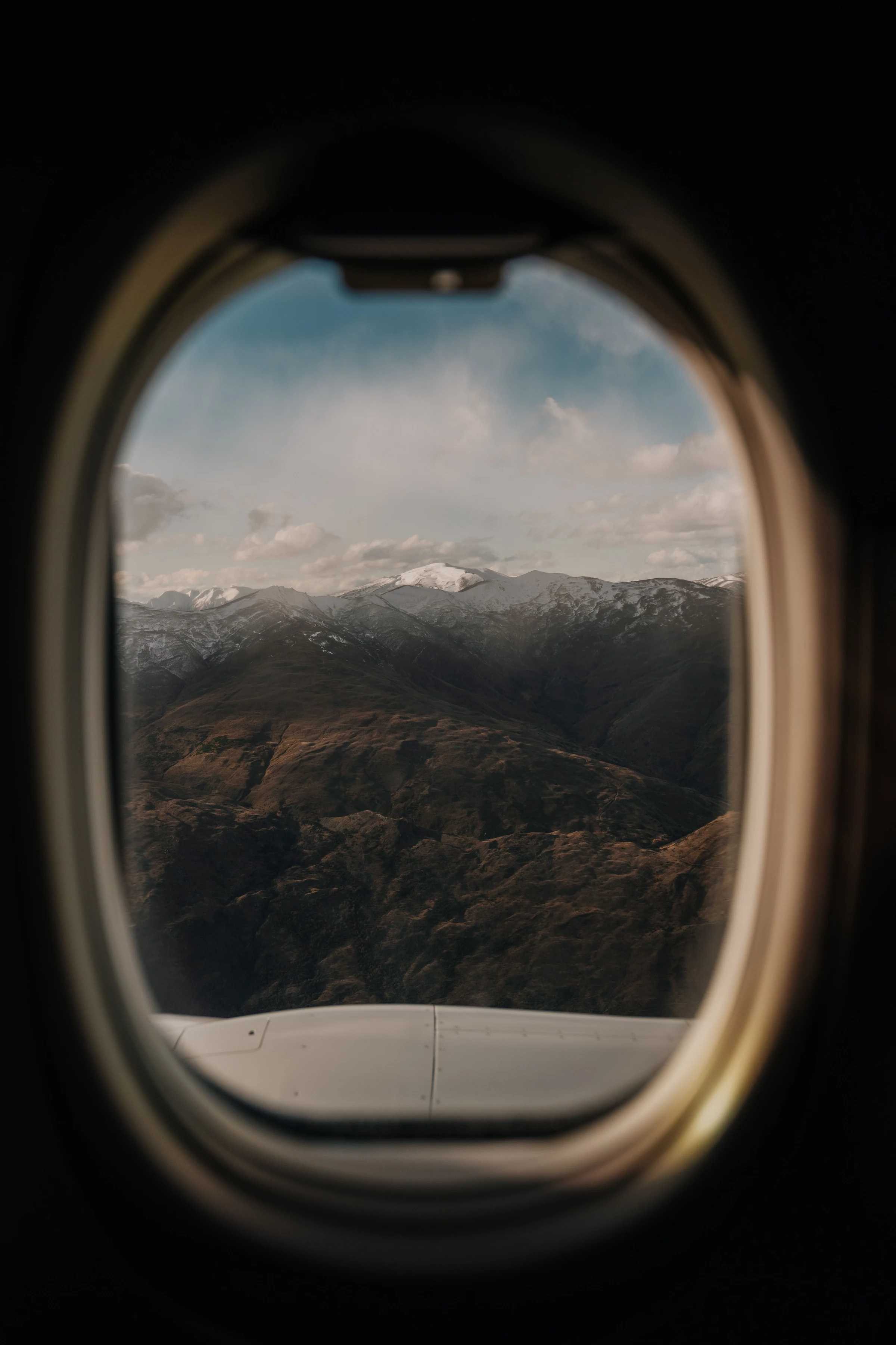 Snow-dusted mountains seen through an aircraft window