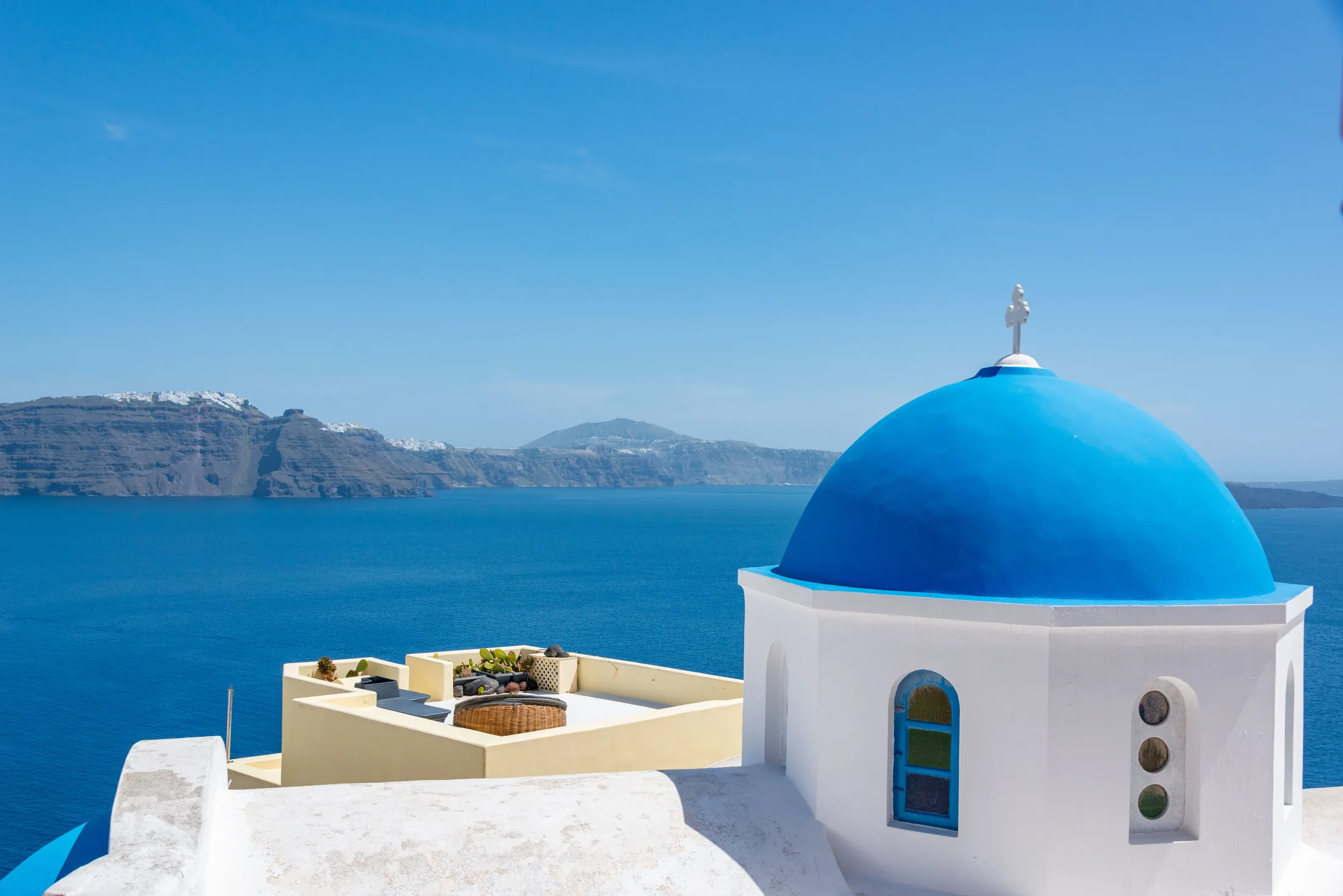 Blue church dome and white buildings above Santorini’s caldera