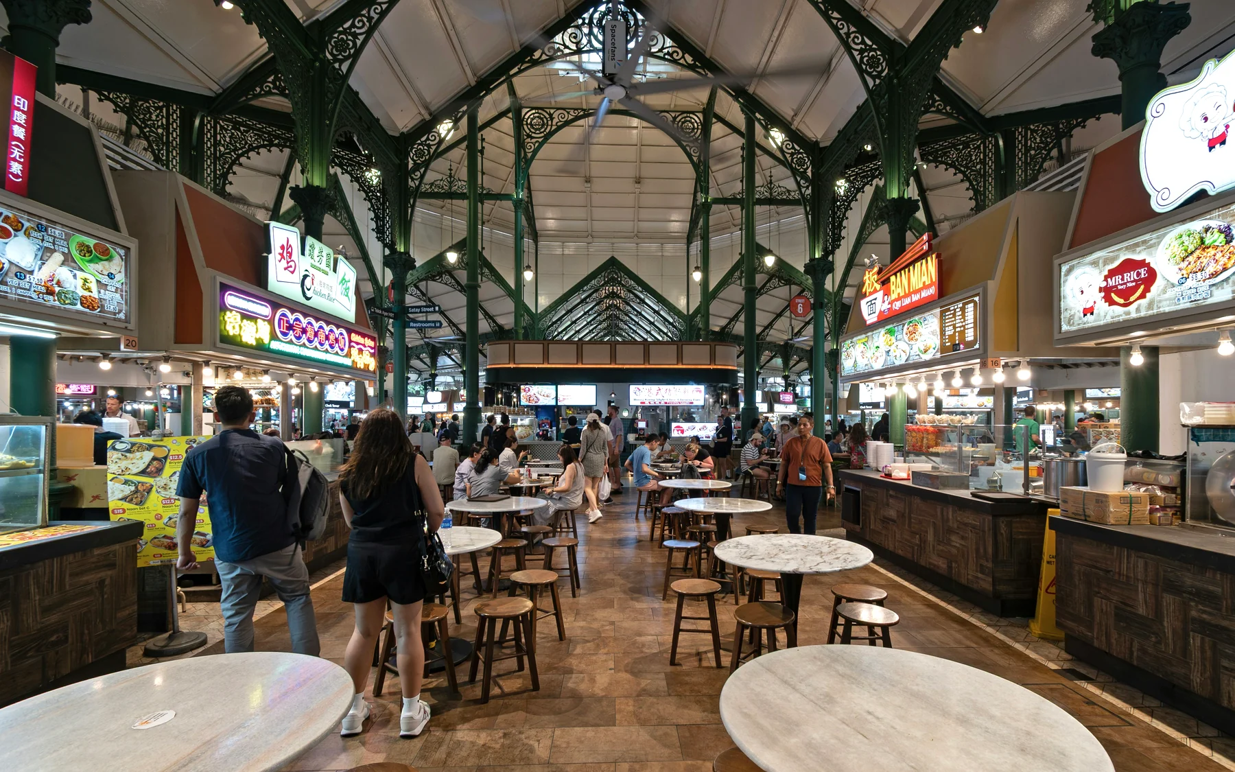 Food stalls and shared dining tables beneath the ironwork roof of Lau Pa Sat in Singapore