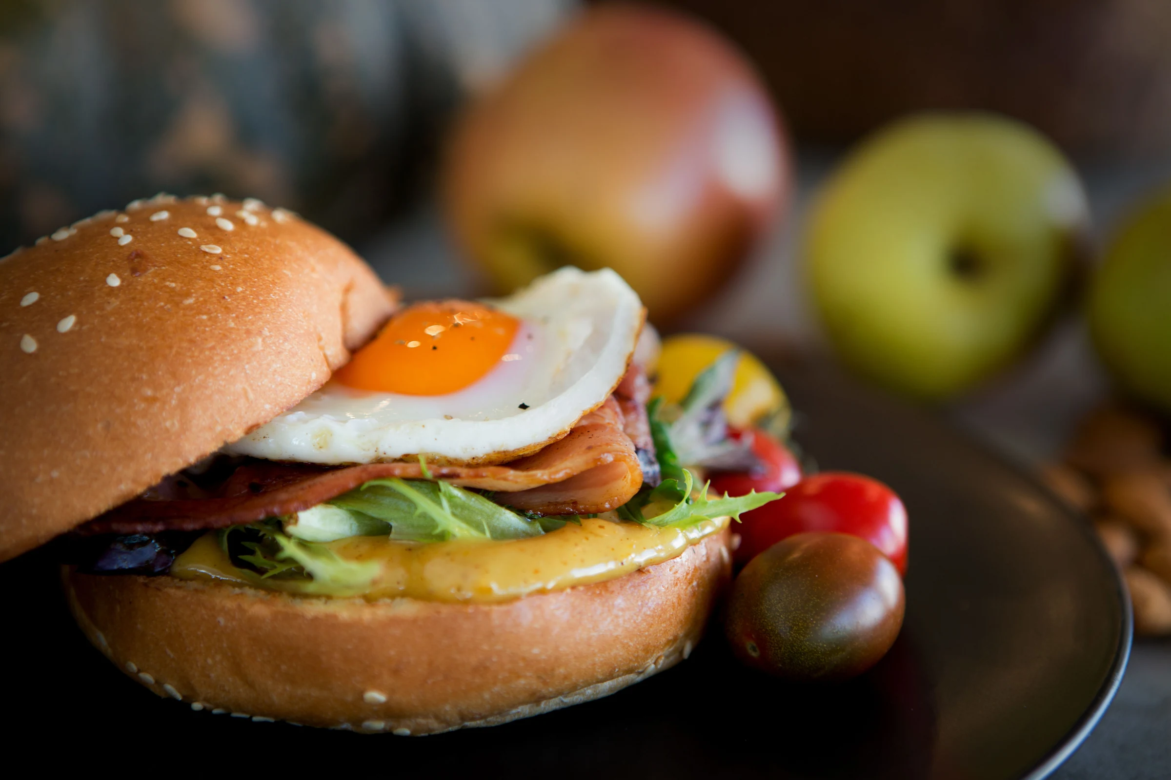 Burger topped with a fried egg, bacon, cheese and leafy greens