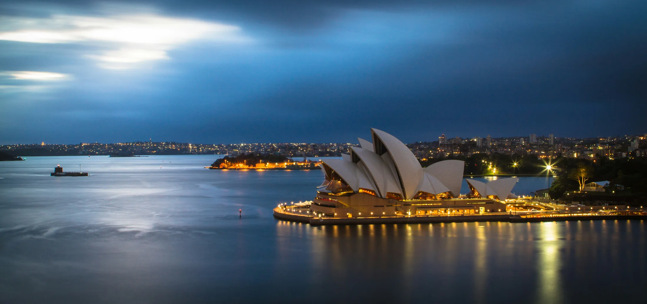 Sydney Opera House beside the harbor at dusk