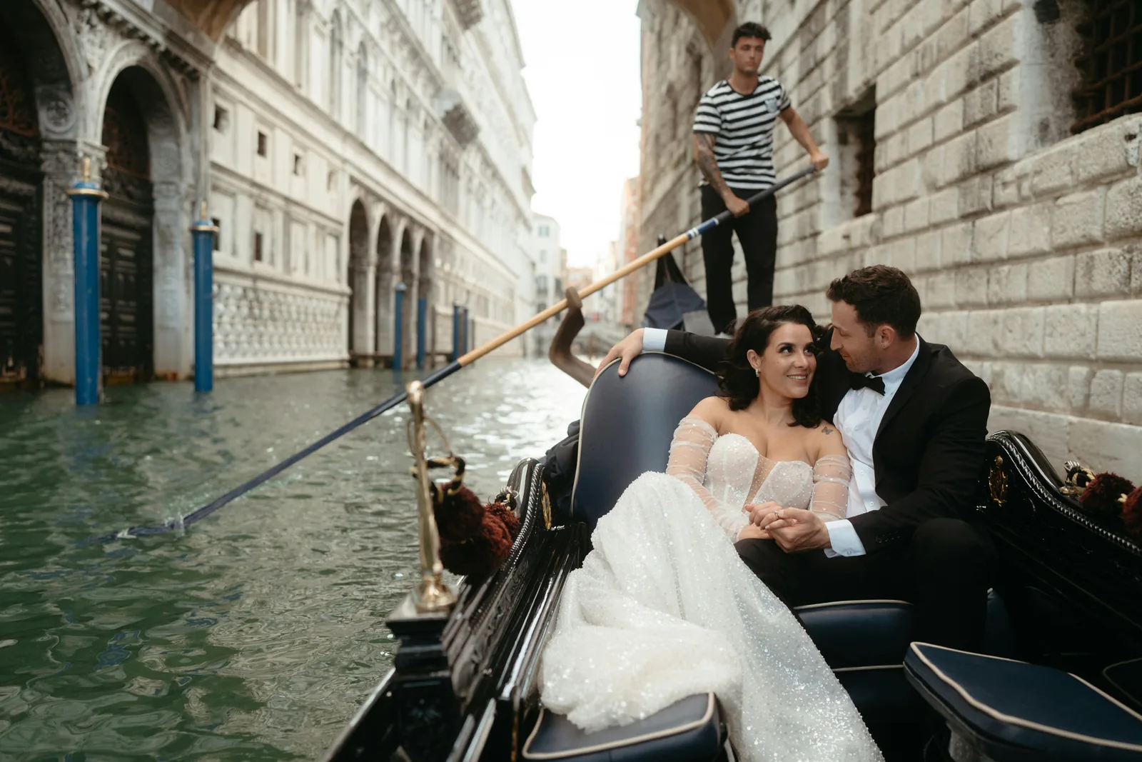Newlyweds sharing a quiet moment in a gondola on a Venice canal