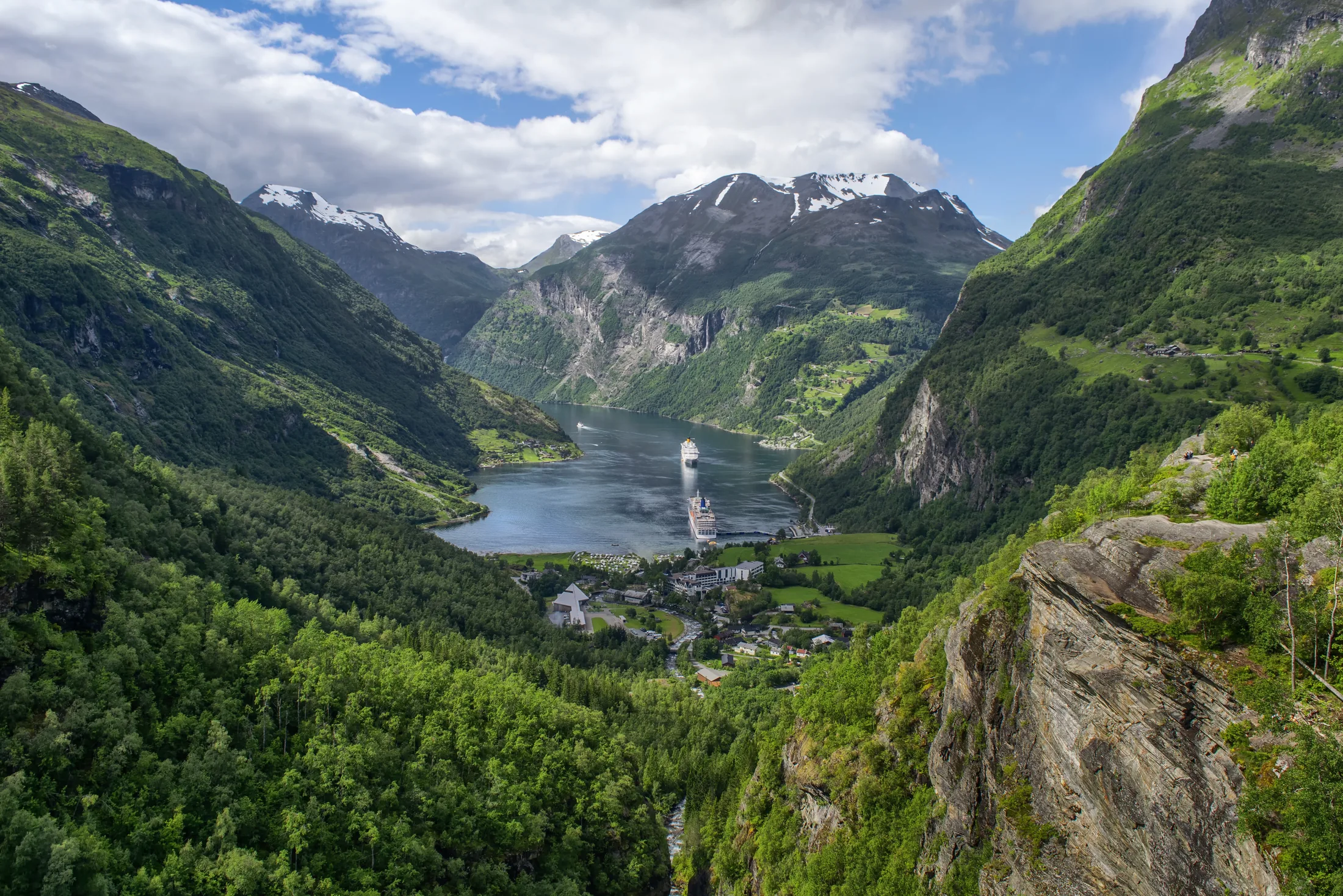 Cruise ship sailing through a steep-sided green mountain inlet