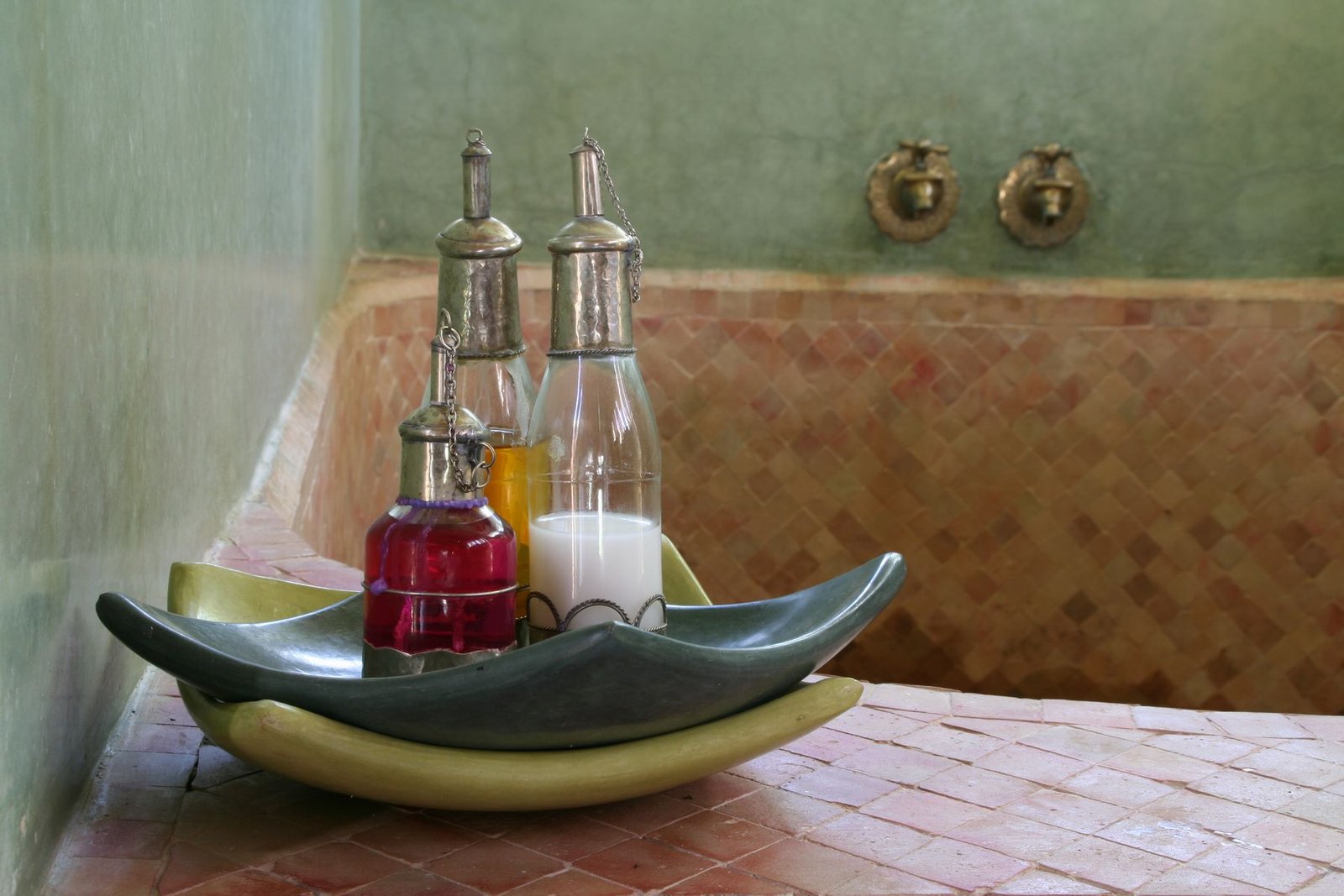Traditional bottles beside a tiled bath in a Marrakech hammam