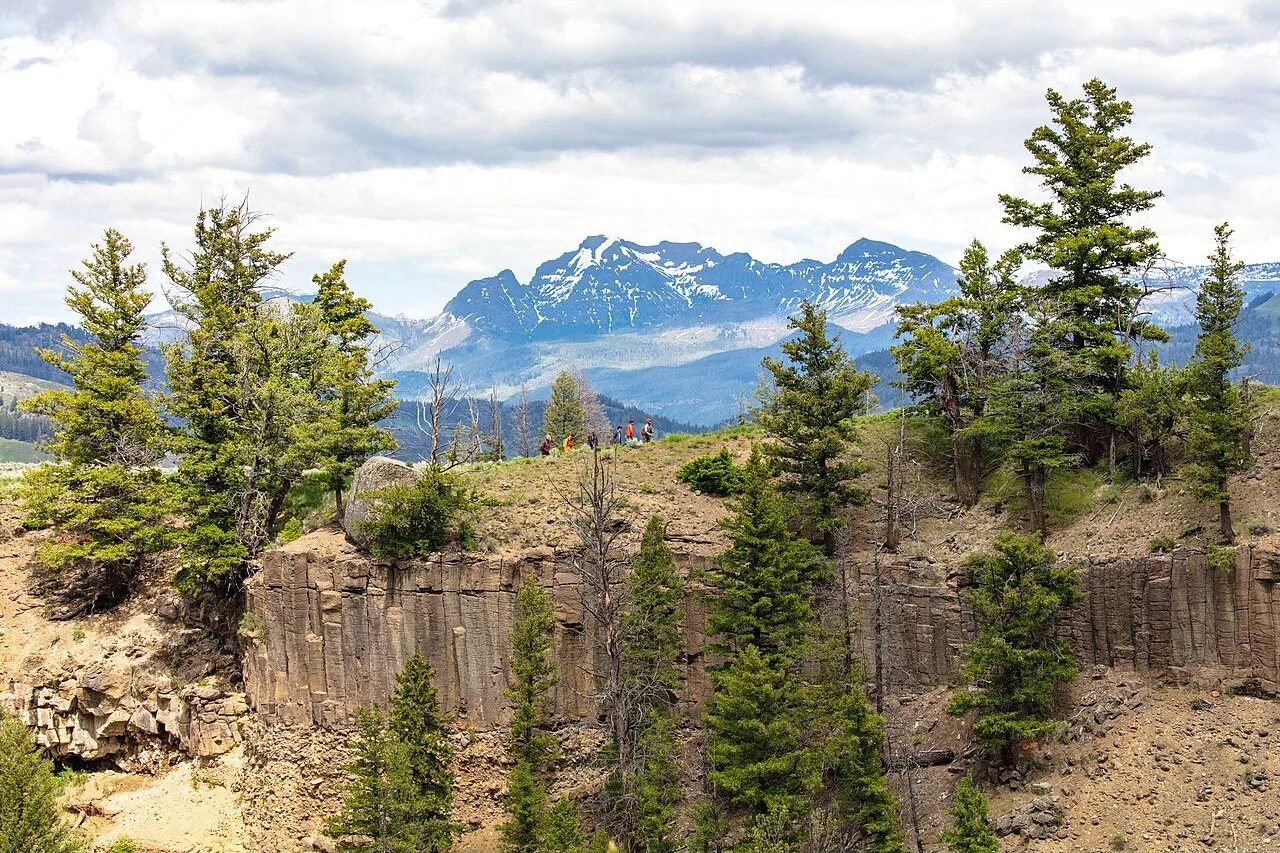 Hikers on Yellowstone River Picnic Area Trail amid trees and rocky cliffs