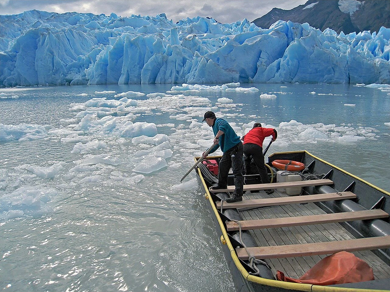 A small boat on ice-strewn water below Grey Glacier in Patagonia