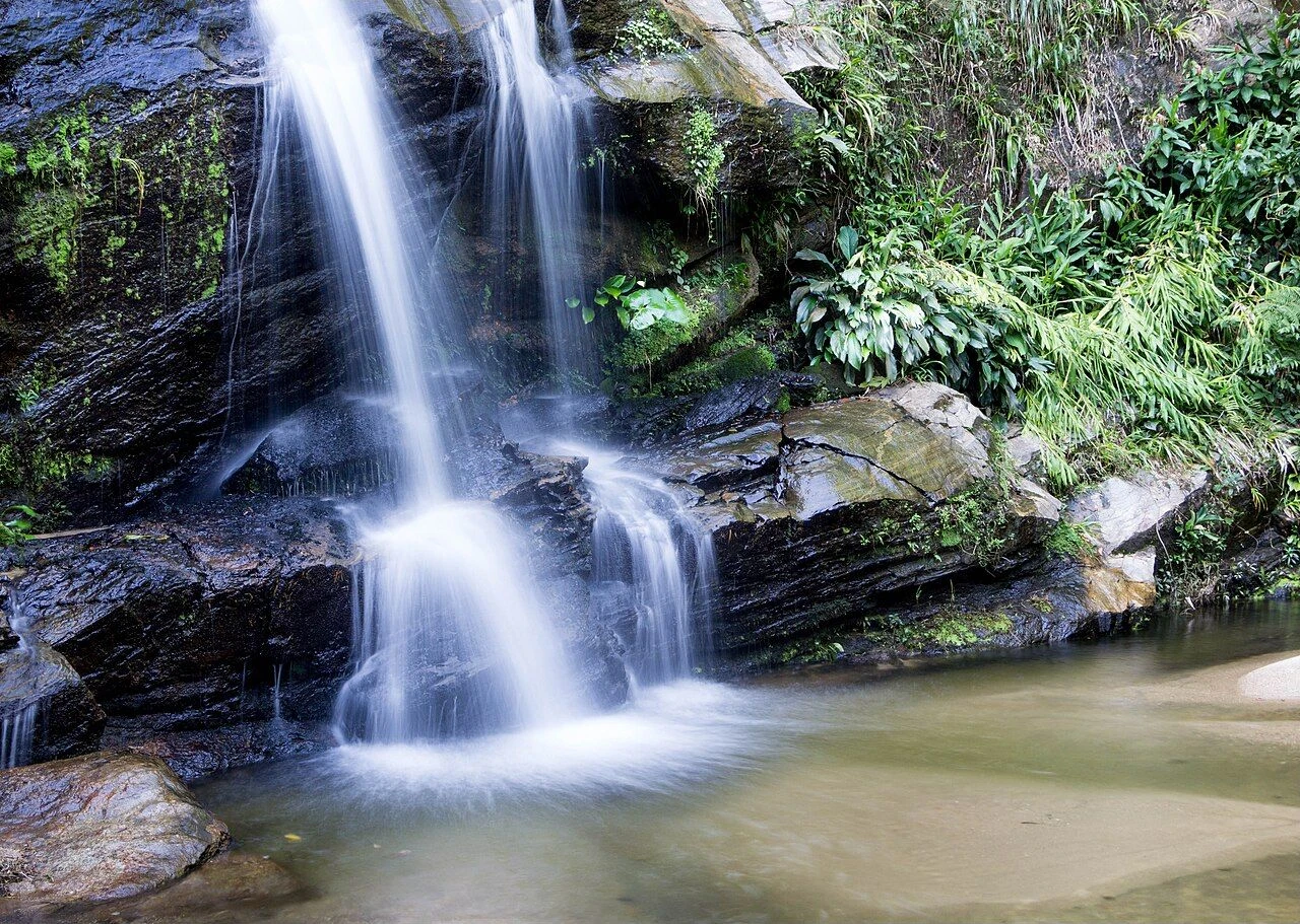 Cascatinha waterfall flowing over rocks amid Tijuca Forest vegetation