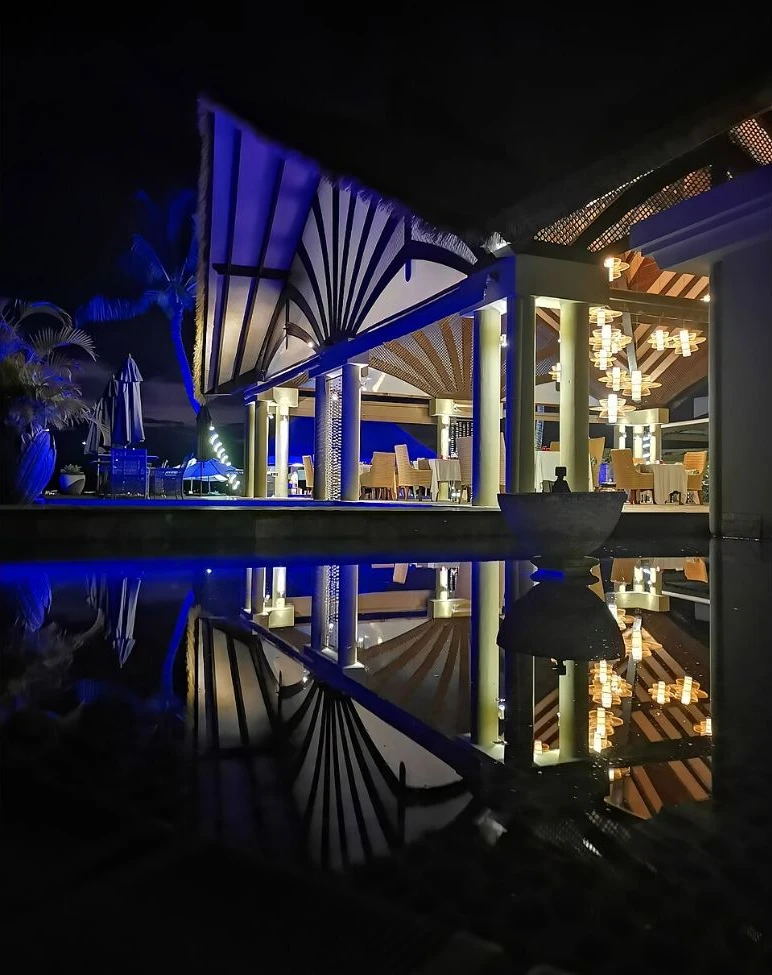 Illuminated resort terrace reflected in water on La Digue