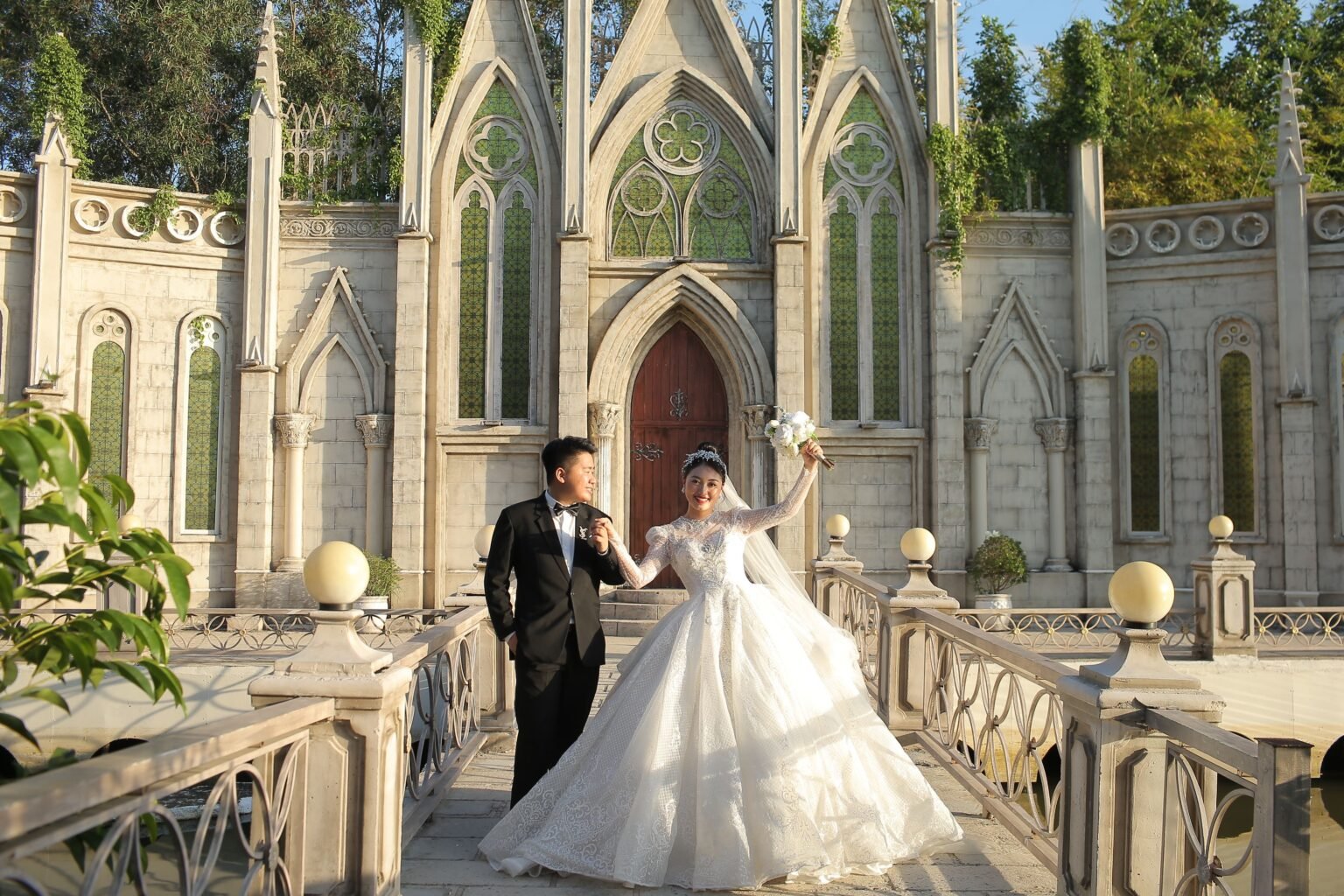 A wedding couple celebrating in front of an ornate stone chapel