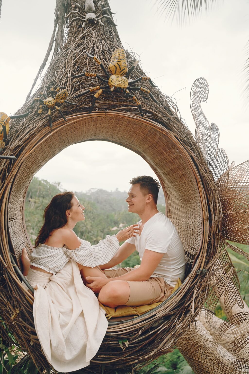A couple relaxing in a woven nest seat overlooking tropical greenery