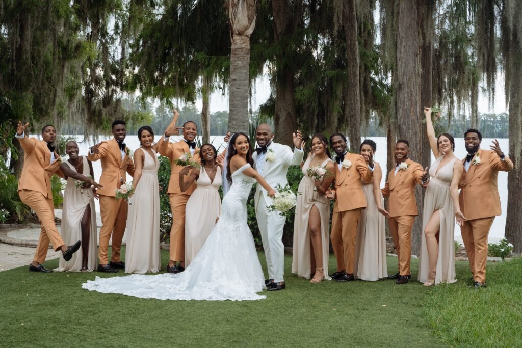A wedding couple celebrating outdoors with their wedding party beneath trees