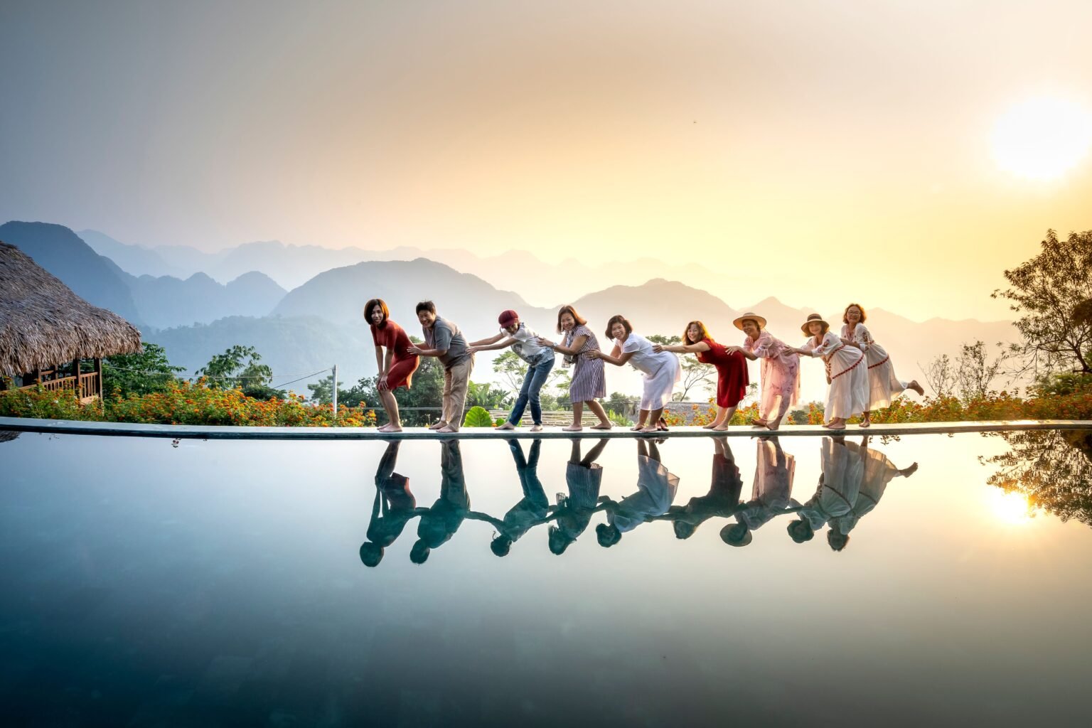 Friends posing beside a reflective pool with mountains at sunset