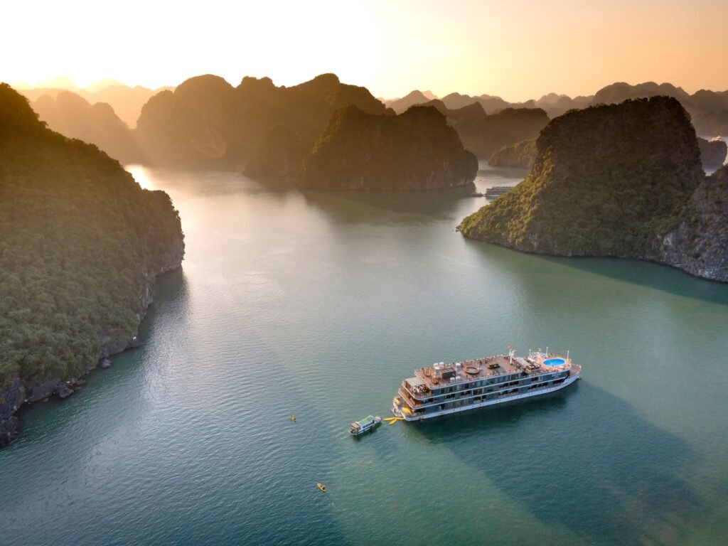 A small cruise ship among limestone islands at sunset