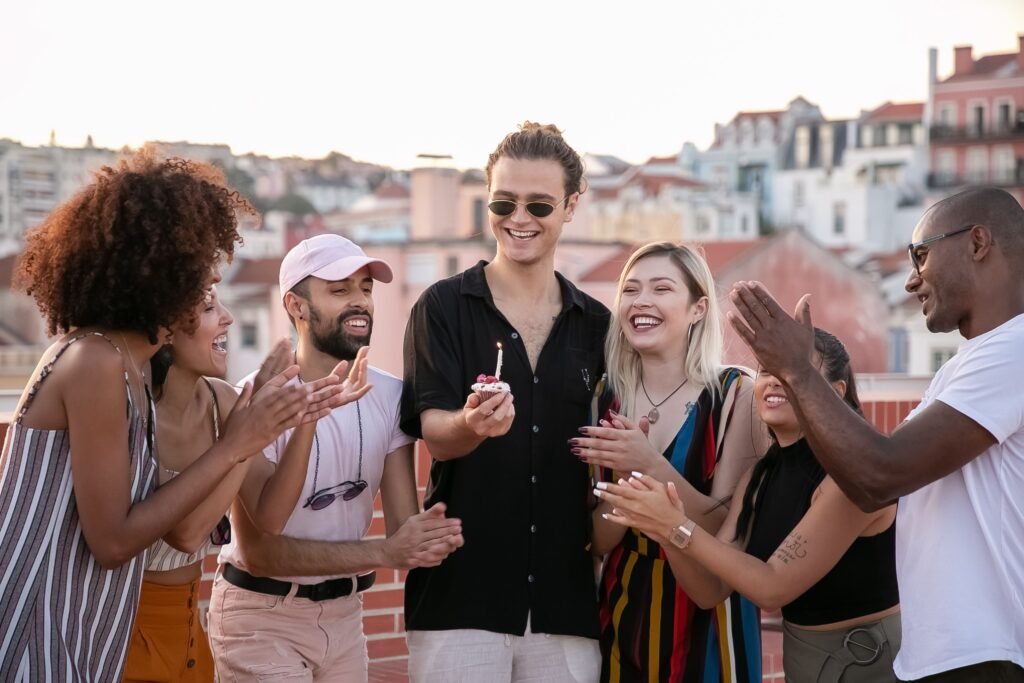 Friends celebrating a birthday on a rooftop with a candle-topped cupcake