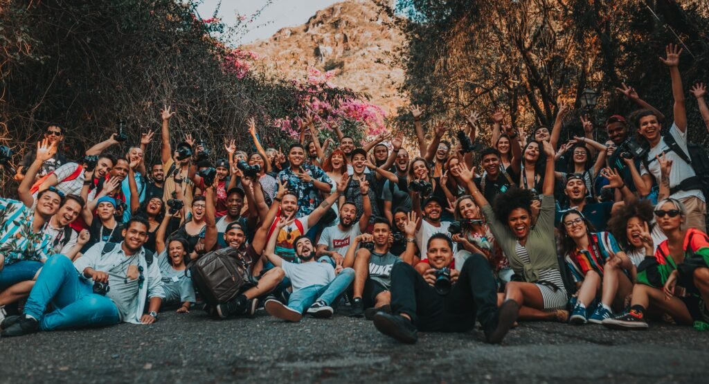 A large group of travelers smiling and waving together outdoors